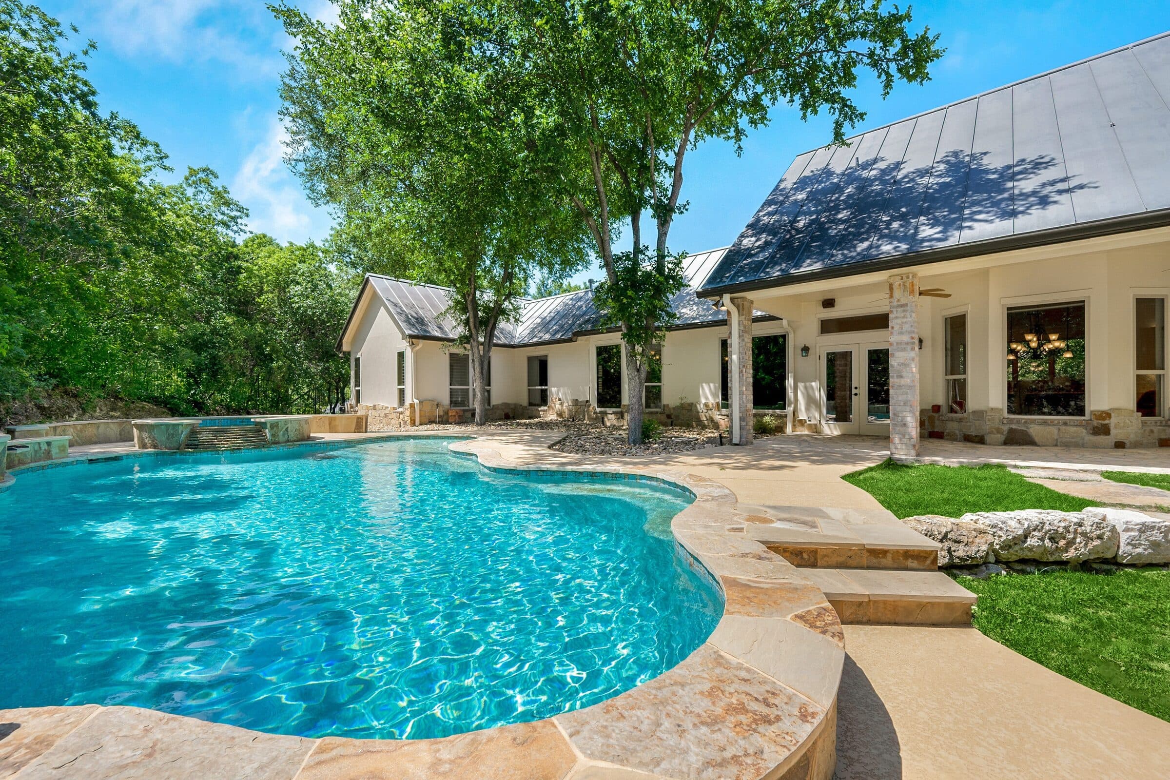 Freeform stone pool with clear blue water on a sunny summer day